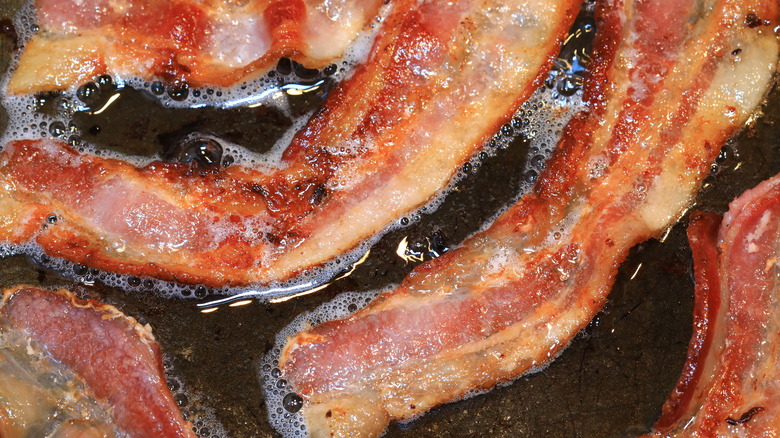 Closeup of cooking bacon in a pan.