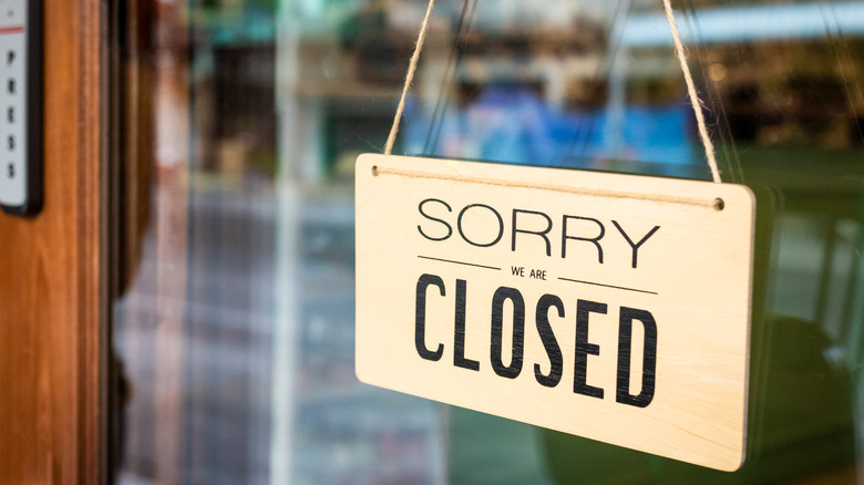 A "sorry, we are closed" sign hangs on a restaurant door