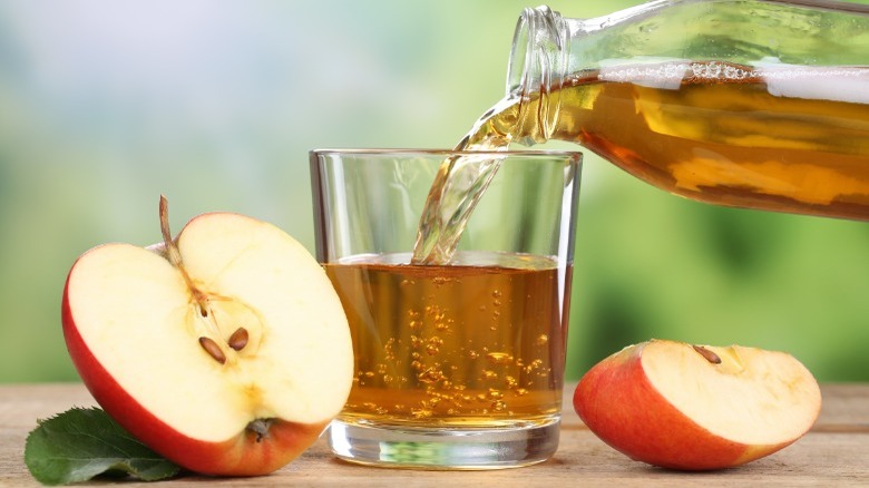 A cut apple and apple juice being poured into a glass