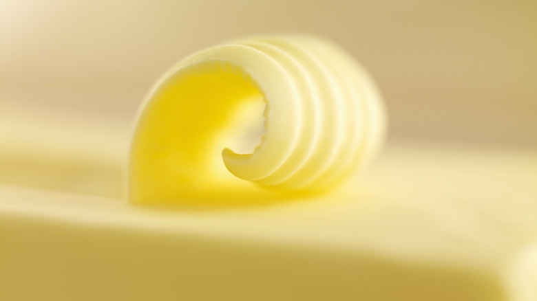 A block of yellow butter with a curl peeled along the top.