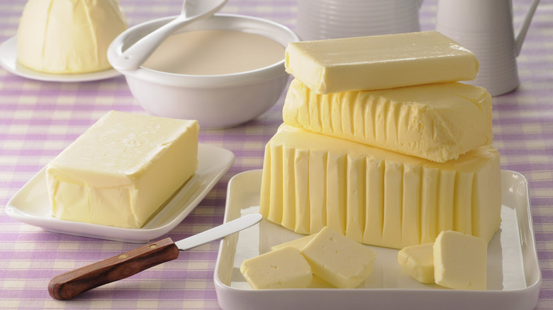 Various types of butter in block form are arranged on a checkered tablecloth.