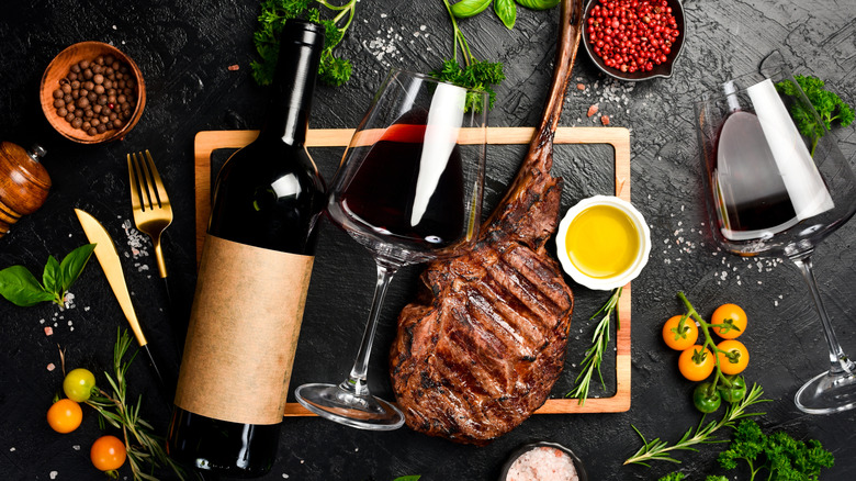 Steak alongside a glass and bottle of red wine