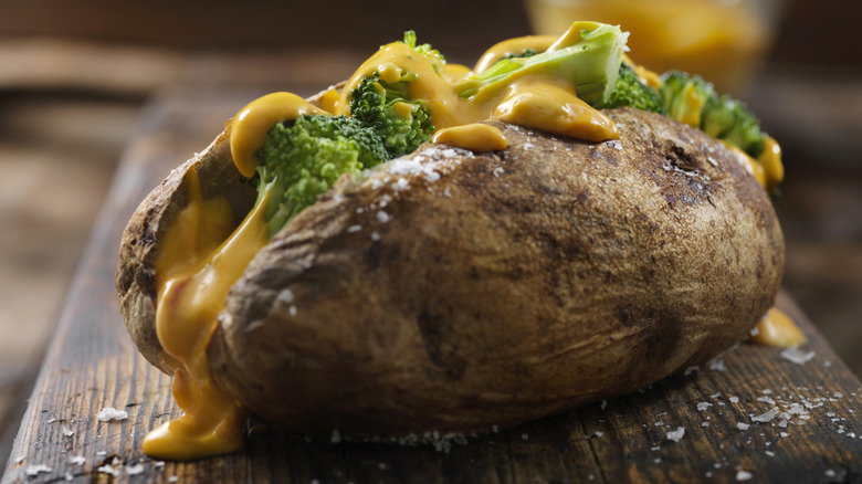 A baked potato stuffed with broccoli and cheese sauce and sprinkled with coarse salt