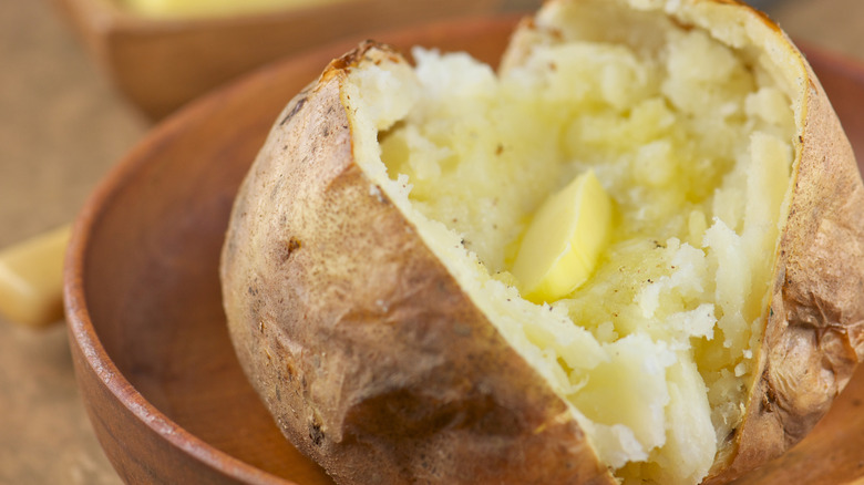 A baked potato is split down the middle with butter melting inside