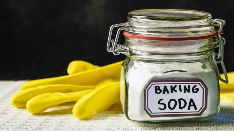jar of baking soda sitting on cloth countertop with yellow glove
