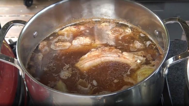 Stainless steel pan of simmering pork ribs with spices