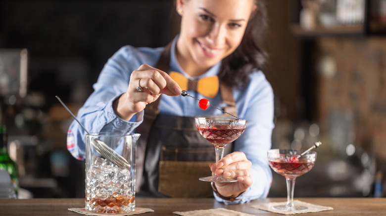 Bartender garnishing Manhattan cocktail