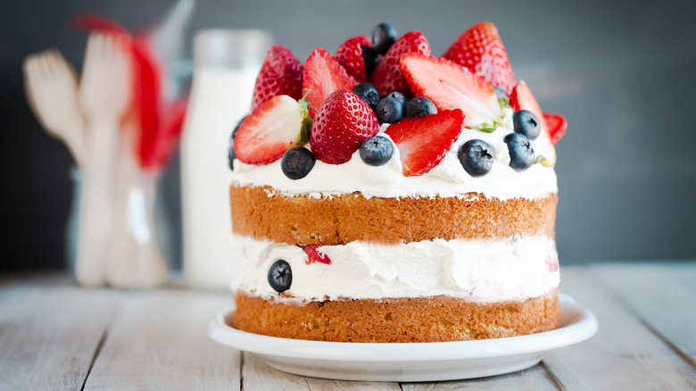 Layered cake with white frosting topped with berries.