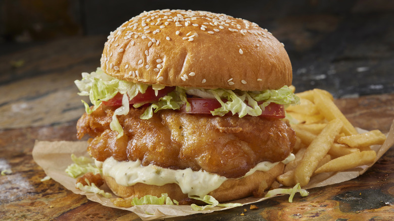 Fried fish sandwich on a bun next to french fries