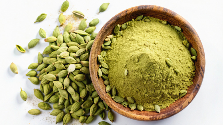 cardamom pods next to a bowl of ground cardamom