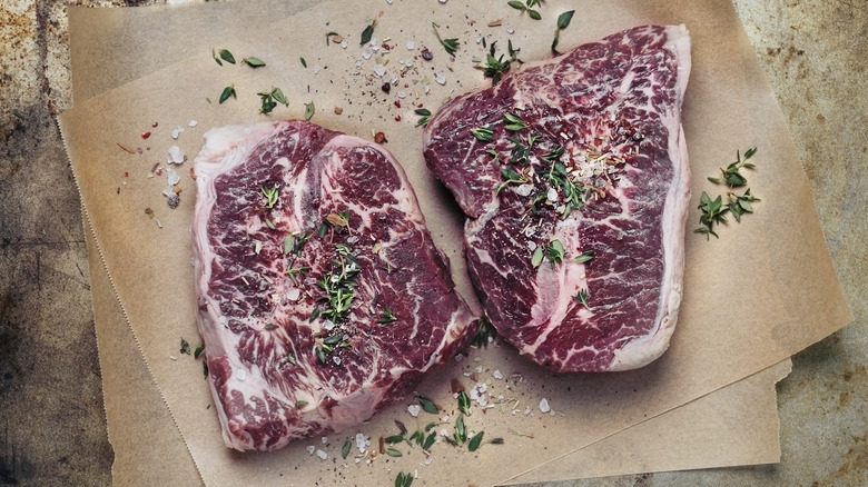 Two raw steaks on some parchment paper