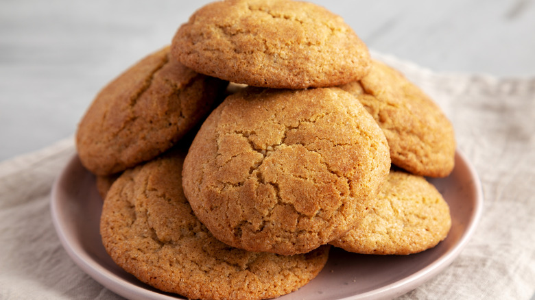 A plate of soft snickerdoodle cookies rests on a linen kitchen towel