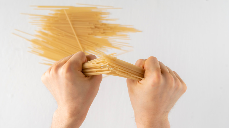 Hands breaking spaghetti in half