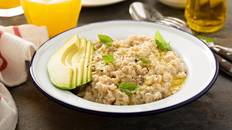 Bowl of oatmeal with olive oil, basil, avocado
