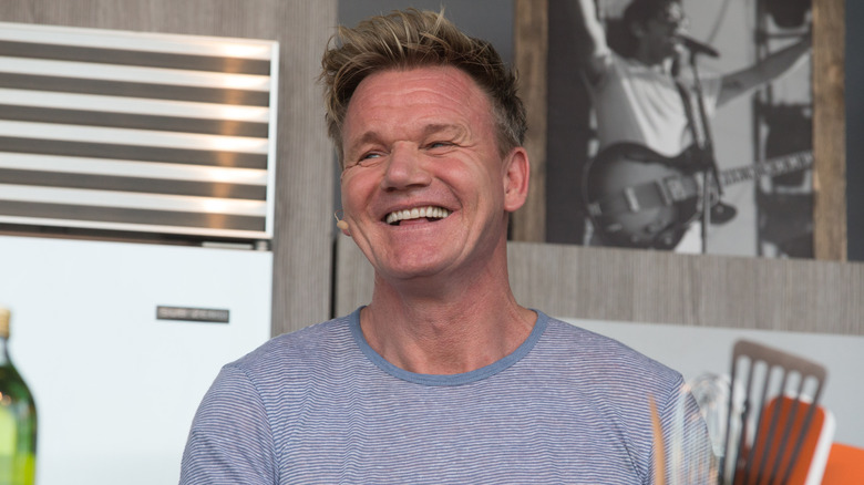 Gordon Ramsay poses in the kitchen with a big smile on his face