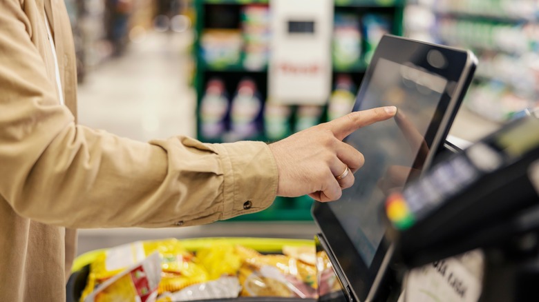 shopper touching self checkout screen