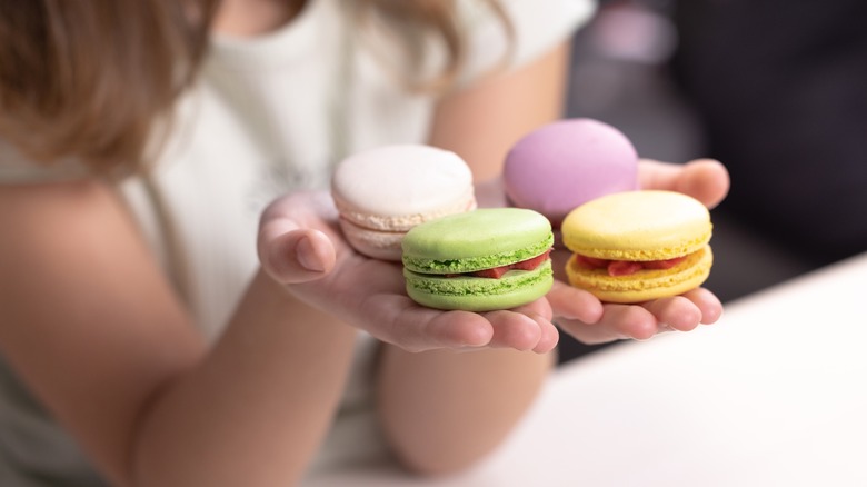Woman holding four colorful macarons