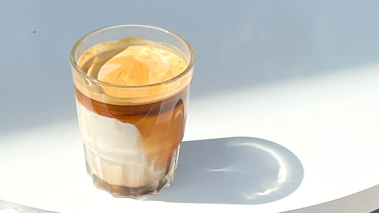 glass of dirty coffee as it marbles on white table