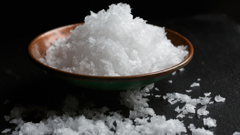 A bowl of Maldon sea salt, aka finishing salt, rests in a bed of spilled Maldon salt