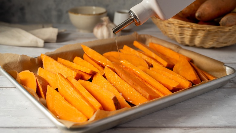 Drizzling olive oil on sweet potato fries before baking