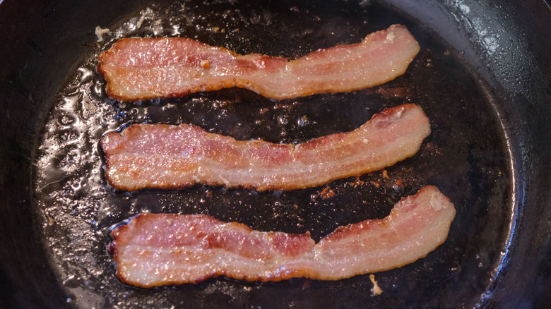 Bacon strips cooking in a skillet