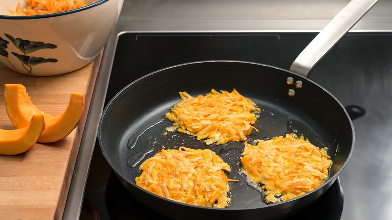 Potato and squash hash browns cooking in pan
