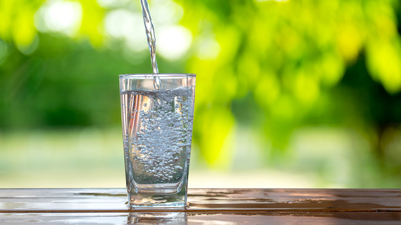 water being poured into a glass on a wooden table