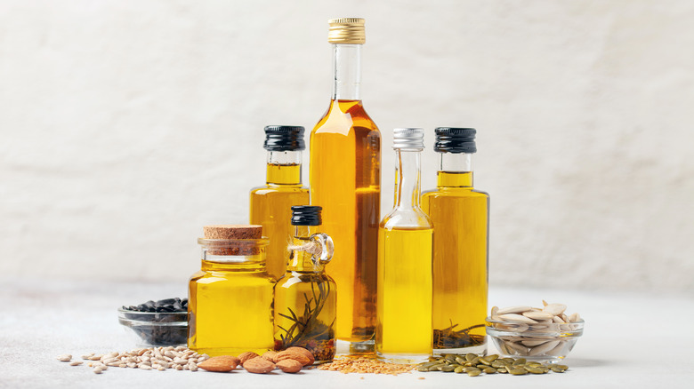 Different sizes and shapes of oil bottles sit arranged with bowls of nuts