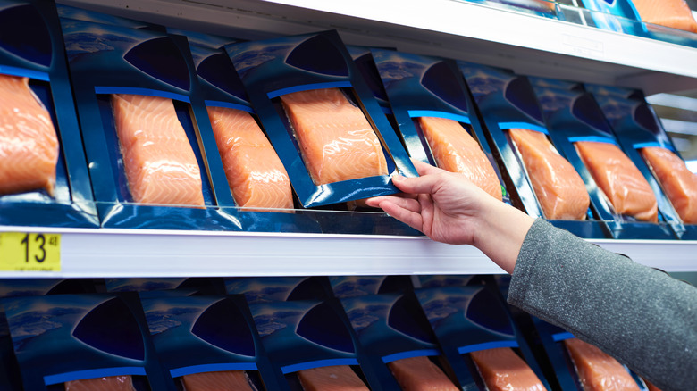 Person picking up salmon from shelf