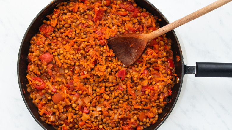 Lentils simmering with tomatoes in pan