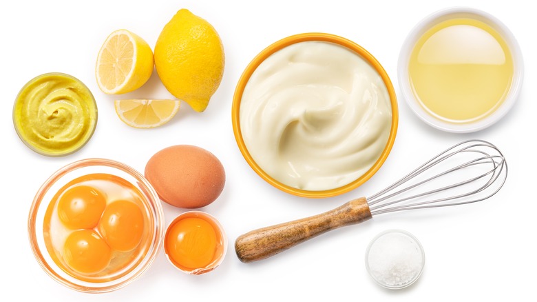 ingredients for making homemade mayonnaise, a whisk, and a bowl full of mayo
