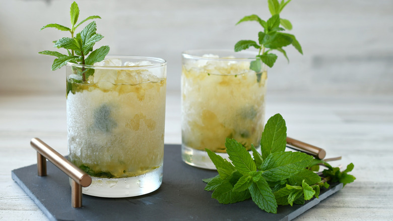 Two mint julep cocktails made with crushed ice on a tray