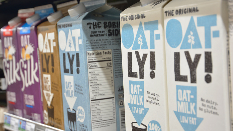 Cartons of Oatly oat milk sit on a grocery store shelf