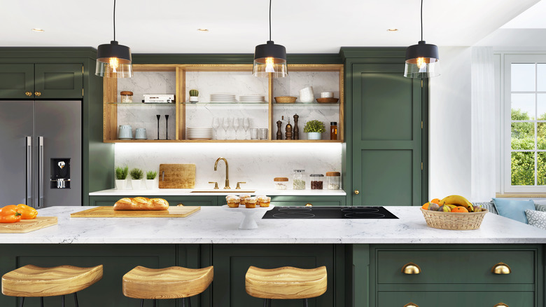 A kitchen with green cabinets, a large island, and open shelving above the sink