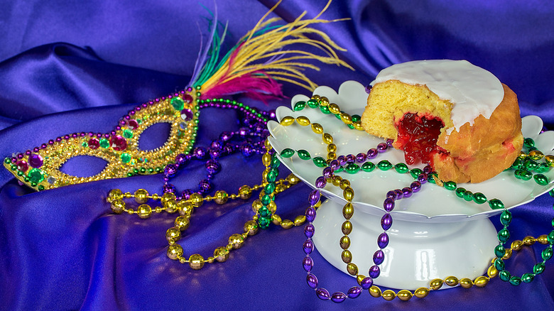 Paczki jelly filled donut on cake stand with Mardi Gras beads and sequined mask