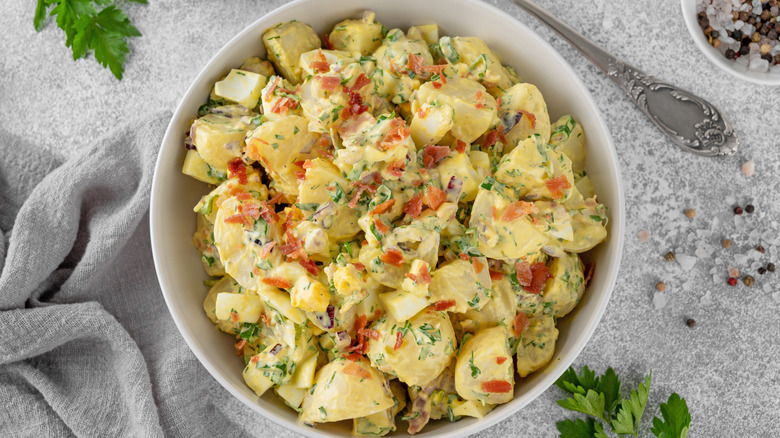 A bowl of potato salad topped with bacon bits