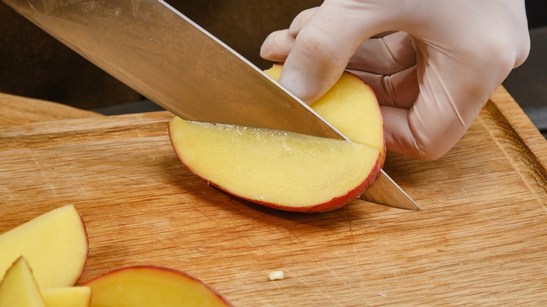 gloved hand chopping potato