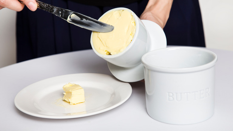 Woman spreading butter from butter crock