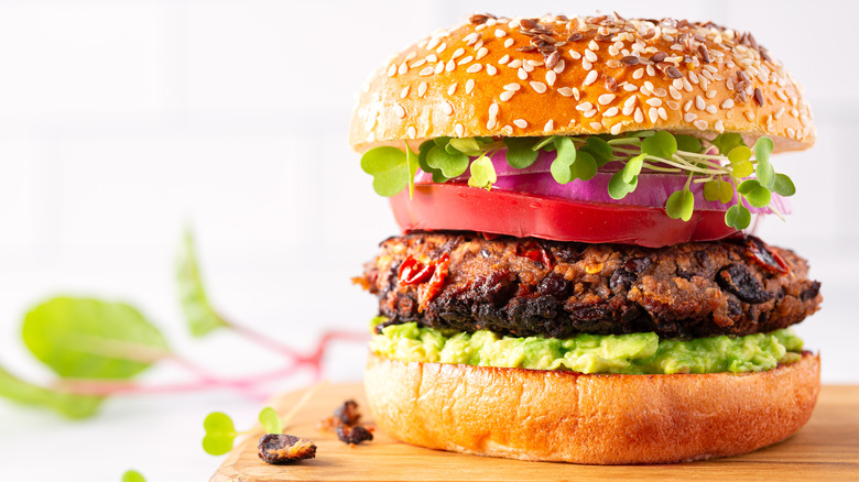 Black bean veggie burger with tomato, red onion, sprouts, and guacamole