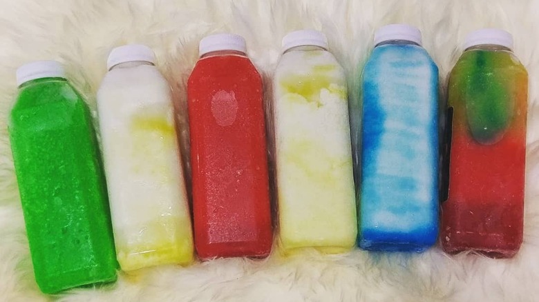 six plastic bottles filled with colorful fruit juice