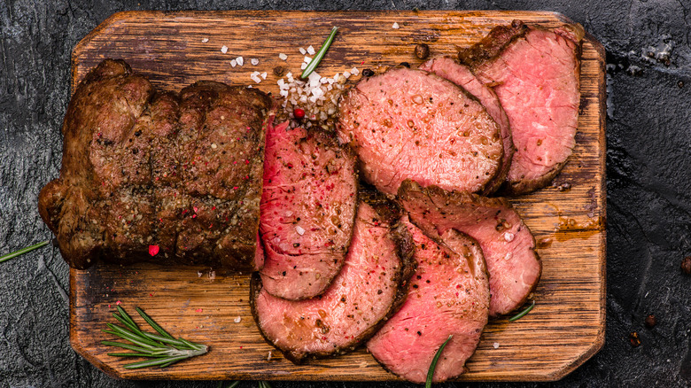 beef tenderloin sliced on a cutting board with coarse salt