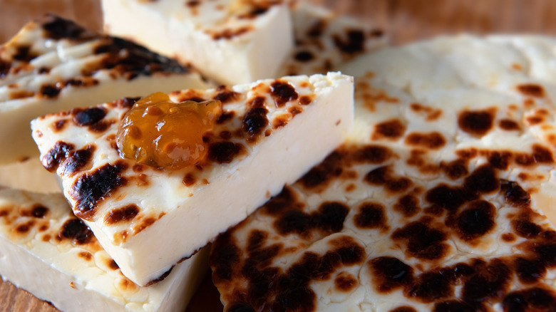 Slice of bread cheese resting on more cheese with a dollop of cloudberry jam