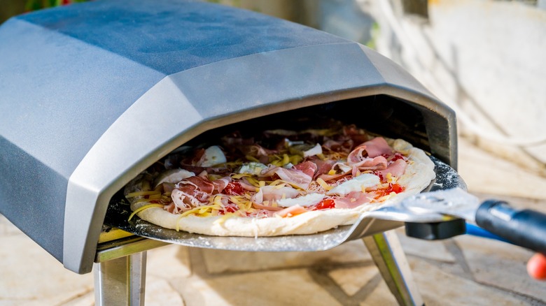 uncooked pizza going into a pizza oven