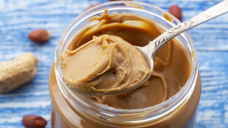 Open peanut butter jar with a spoon