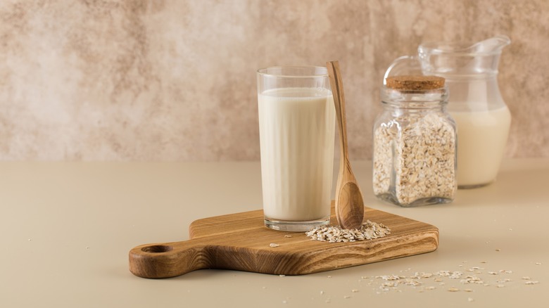 Glass of oat milk, wooden spoon, and oats