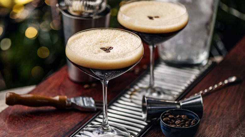 espresso martinis sit on a bar, topped with three espresso beans