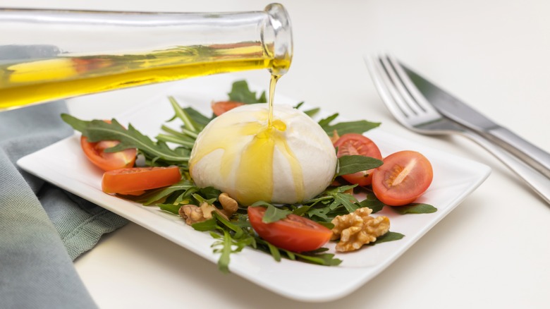 Oil being drizzled on a burrata salad