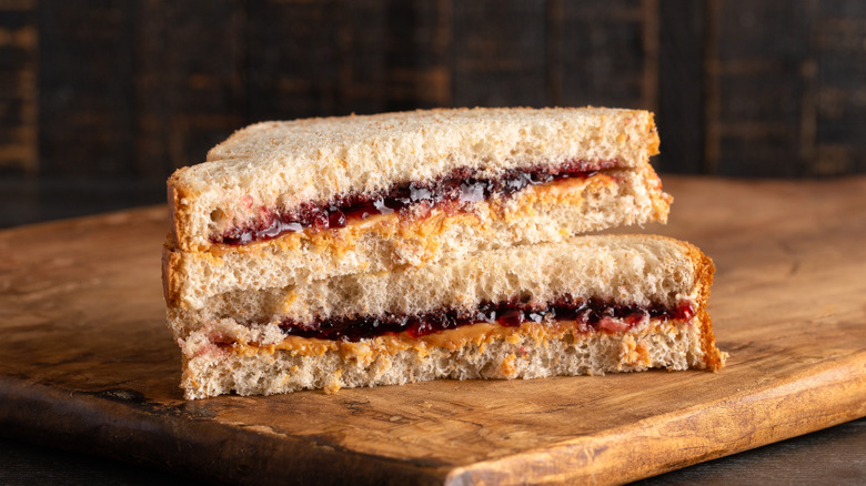 Peanut butter and jelly sandwich cut in half on a wooden board