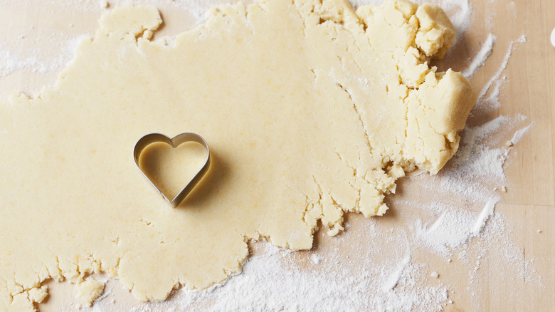 Rolled out sugar cookie dough with heart cookie cutter