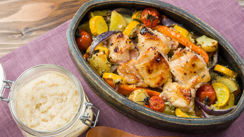 A roast chicken and vegetable plate next to a jar of shio koji